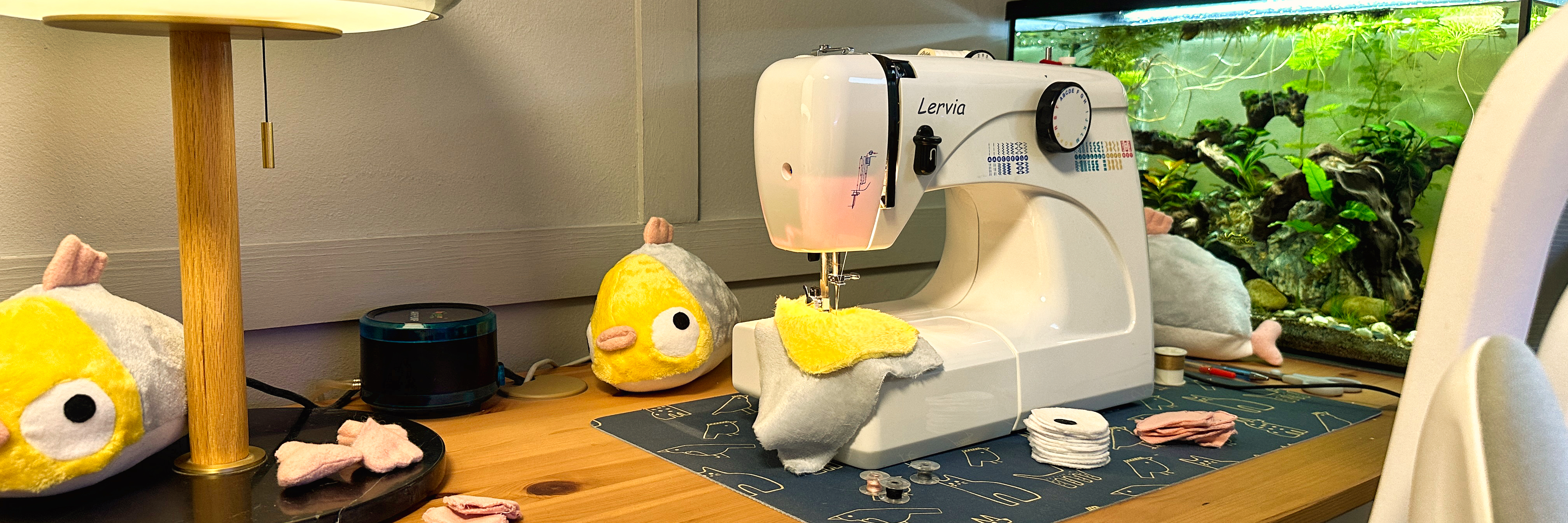 Kori plushies and sewing in progress beside the aquarium